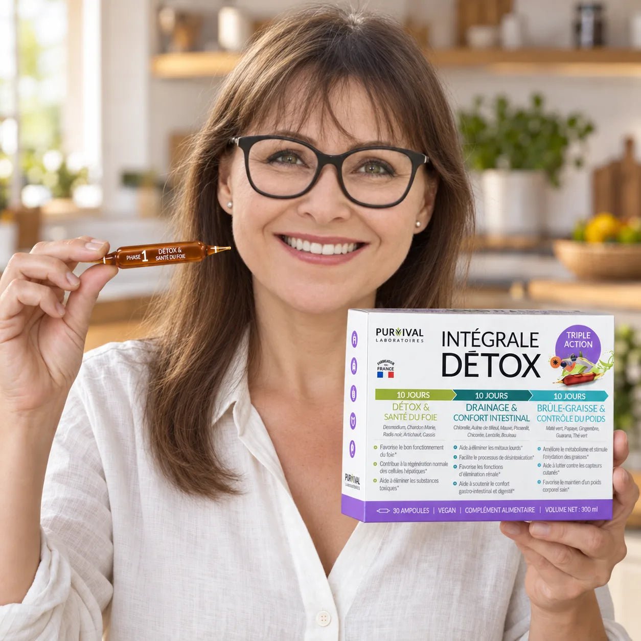 Femme souriante tenant une ampoule et le coffret Intégrale Détox