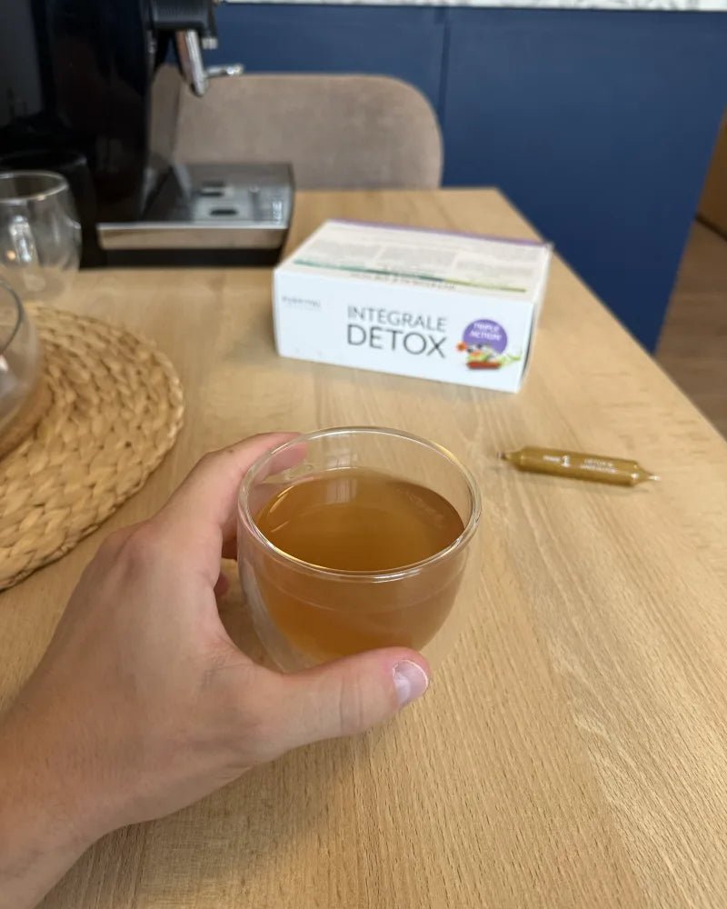Photo client : verre de cure Intégrale Détox tenu en main, coffret et ampoule sur la table